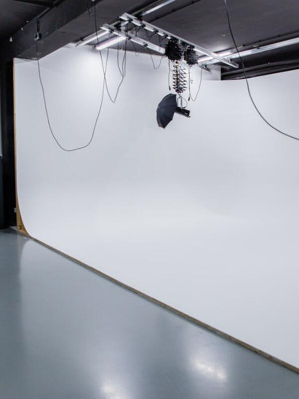 Fotostudio, Beleuchtung mit Schirm hängen von der Decke, weiße Wand und ein Kleiderständer dahinter