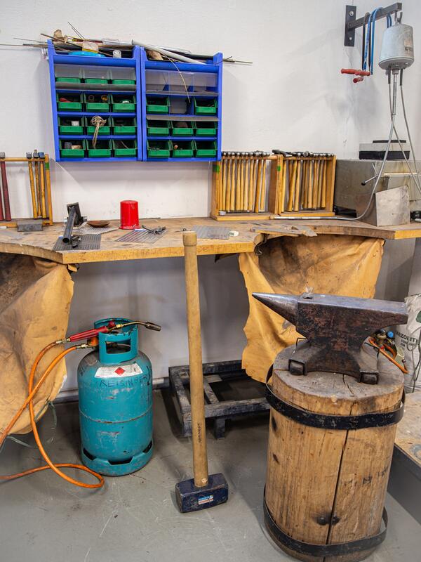 Metallwerkstatt, Werkbank, davor ein großer Amboss 