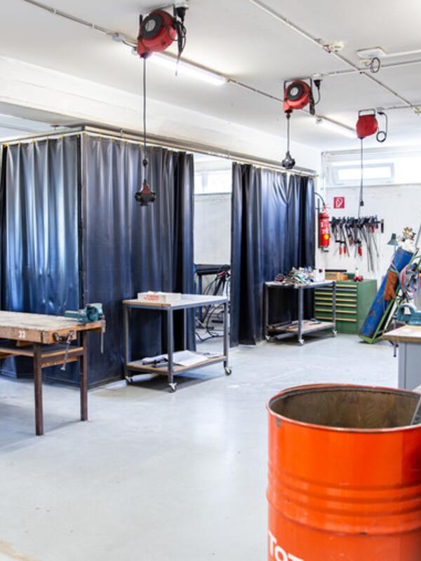 Metallwerkstatt, Arbeitstische, ein Bereich ist mit dunklem Vorhang abgetrennt