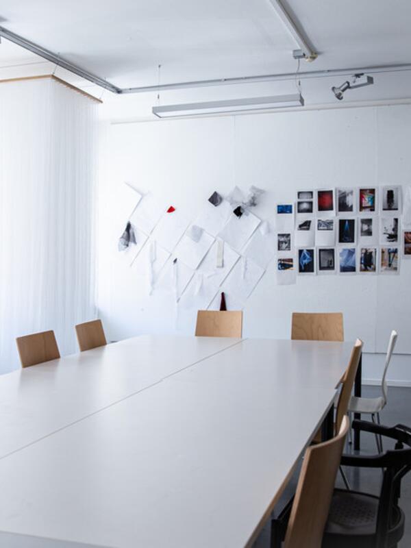 Textilatelier, großer Tisch, dahinter Skizzen an der Wand