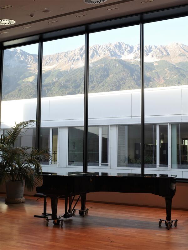 © Elsa Okazaki Konzertsaal mit Piano, Parkettboden, dahinter ein großes Fenster, Blick auf die Nordkette | © Elsa Okazaki