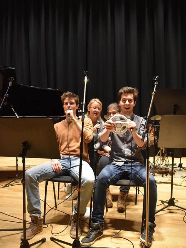 voice & piano | © Musikpädagogik Innsbruck Vier Musiker*innen mit Mikrofon und einem kleinen Lenkrad in den Händen, Notenständer, daneben ein Piano | © Musikpädagogik Innsbruck