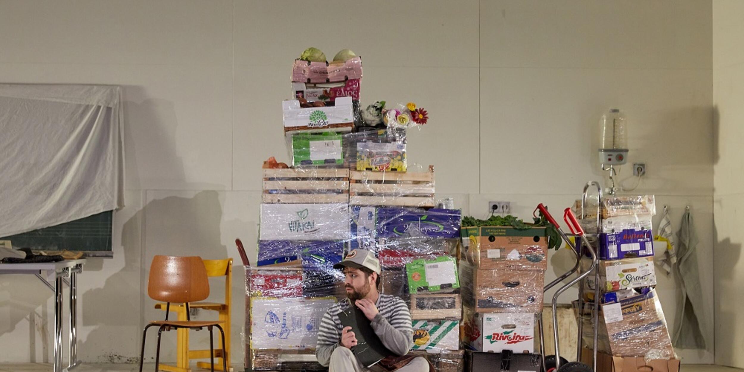 Mann sitzt vor eingepackten Paletten mit Lebensmitteln | © Judith Buss