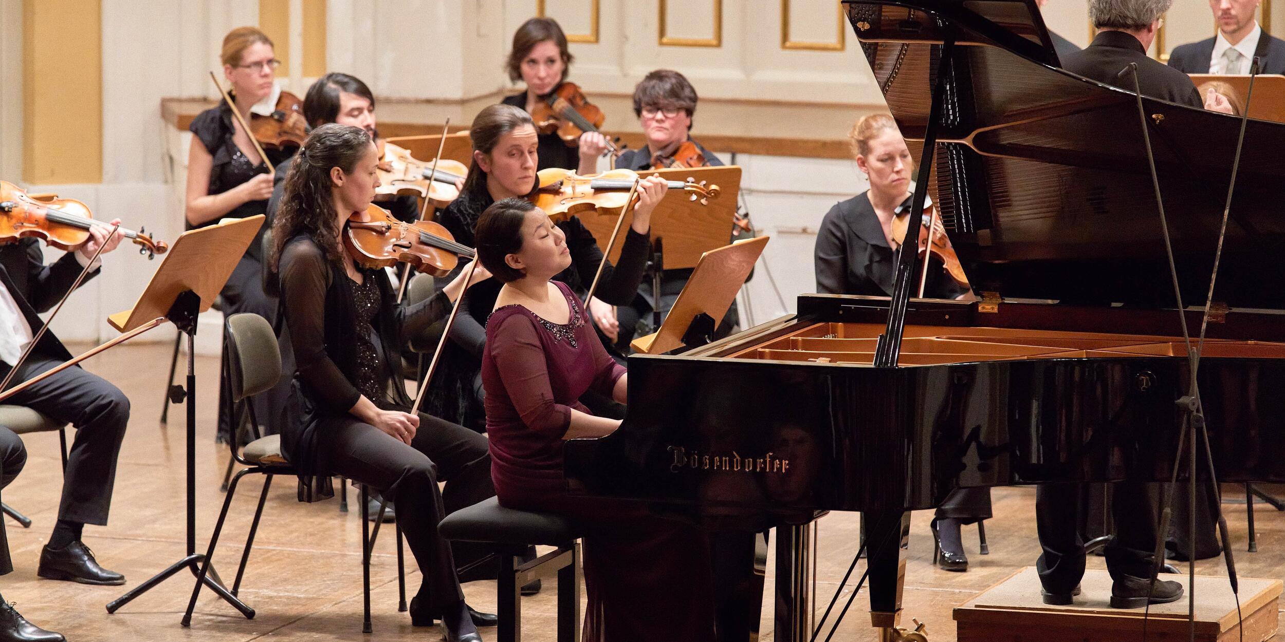 Internationaler Mozartwettbewerb 2016 | © Christian Schneider Pianistin an einem Flügel, dahinter Streicher | © Christian Schneider