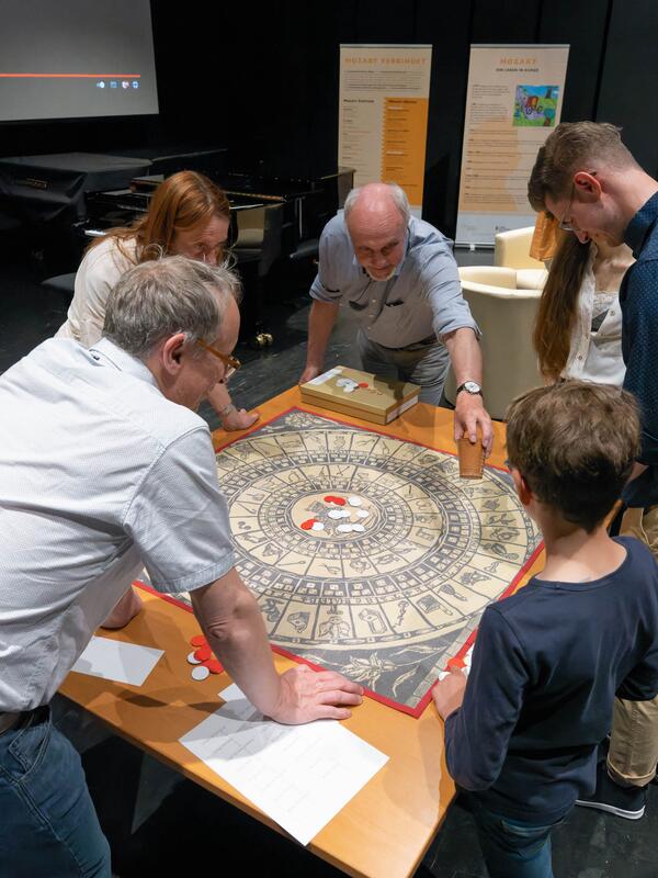 © Christian Schneider Menschen um einen Tisch mit einem alten Brettspiel | © Christian Schneider