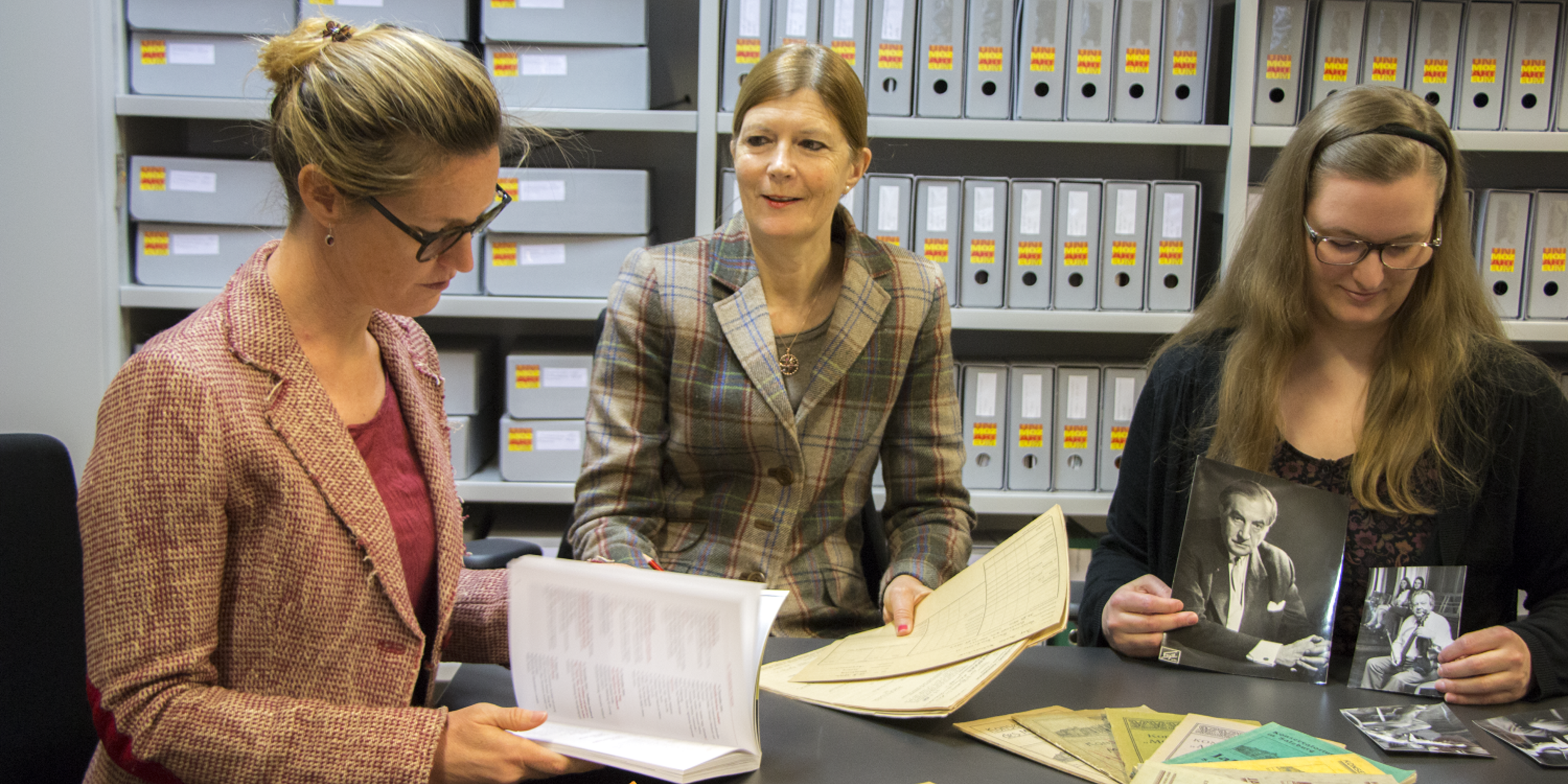 Team des Kunst-Archiv-Raum | © Universität Mozarteum Team des Kunst-Archiv-Raum an einem Tisch mit alten Fotografien und Dokumenten | © Universität Mozarteum