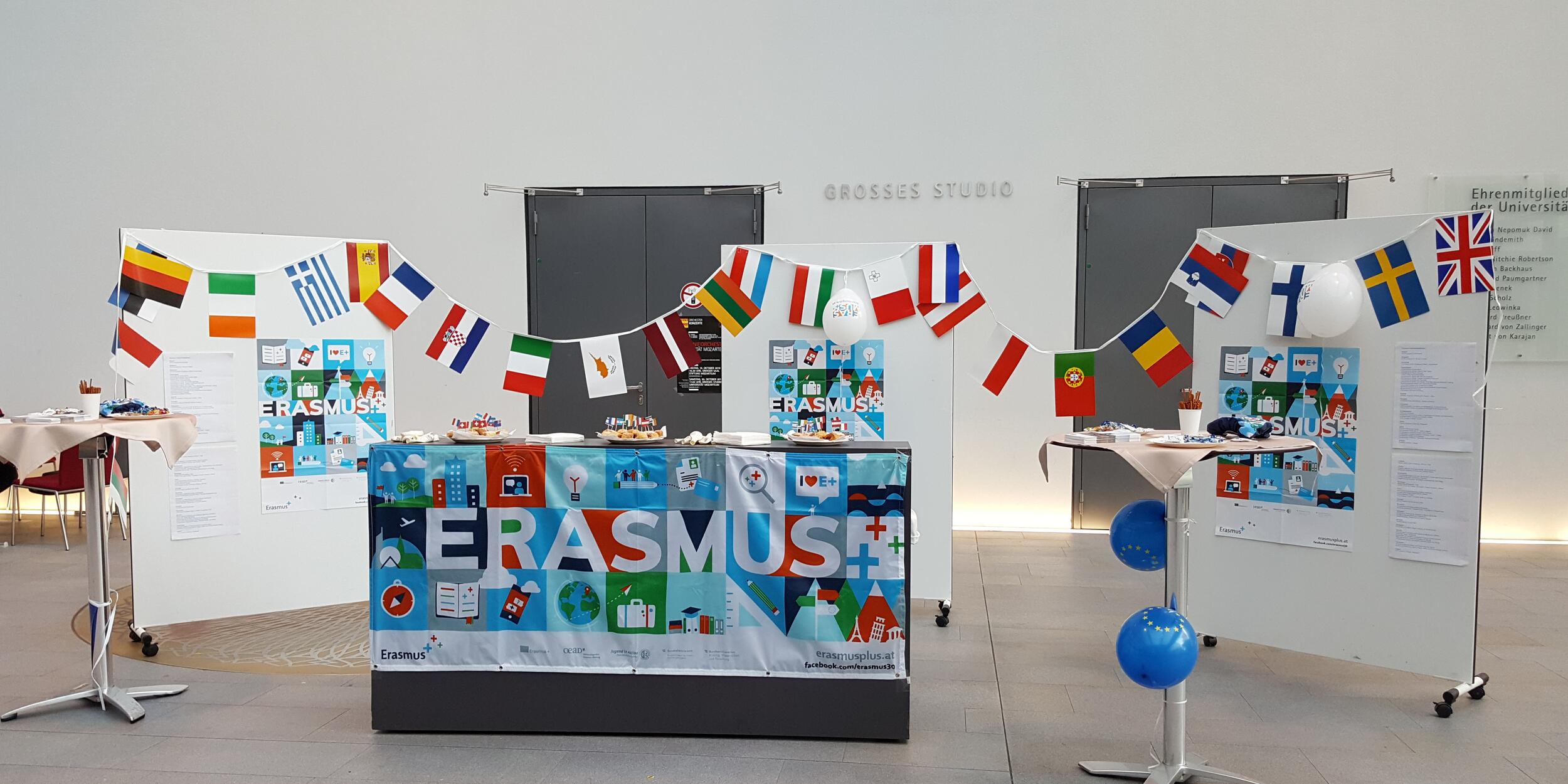 Messestand von Erasmus+, Infotisch, viele internationale Fahnen, blaue Luftballons
