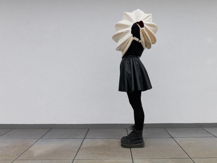Eine Frau verbirgt ihren Kopf in einer Muschel aus Papier | © Sebastian Albert