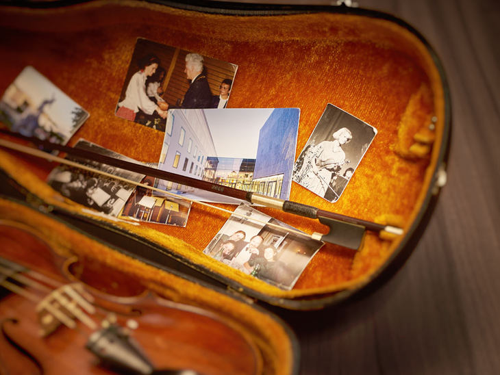 Offener Geigenkasten, darin eine Geige und Fotos der Universität Mozarteum | © Christian Schneider