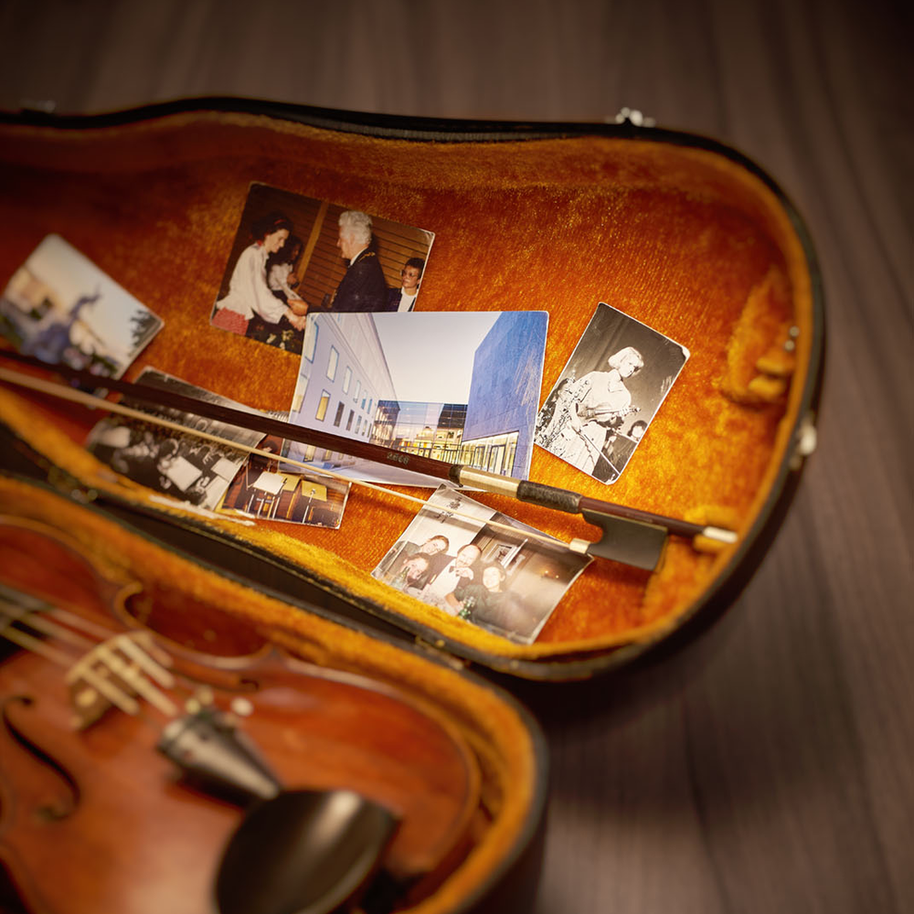 Offener Geigenkasten, darin eine Geige und Fotos der Universität Mozarteum | © Christian Schneider